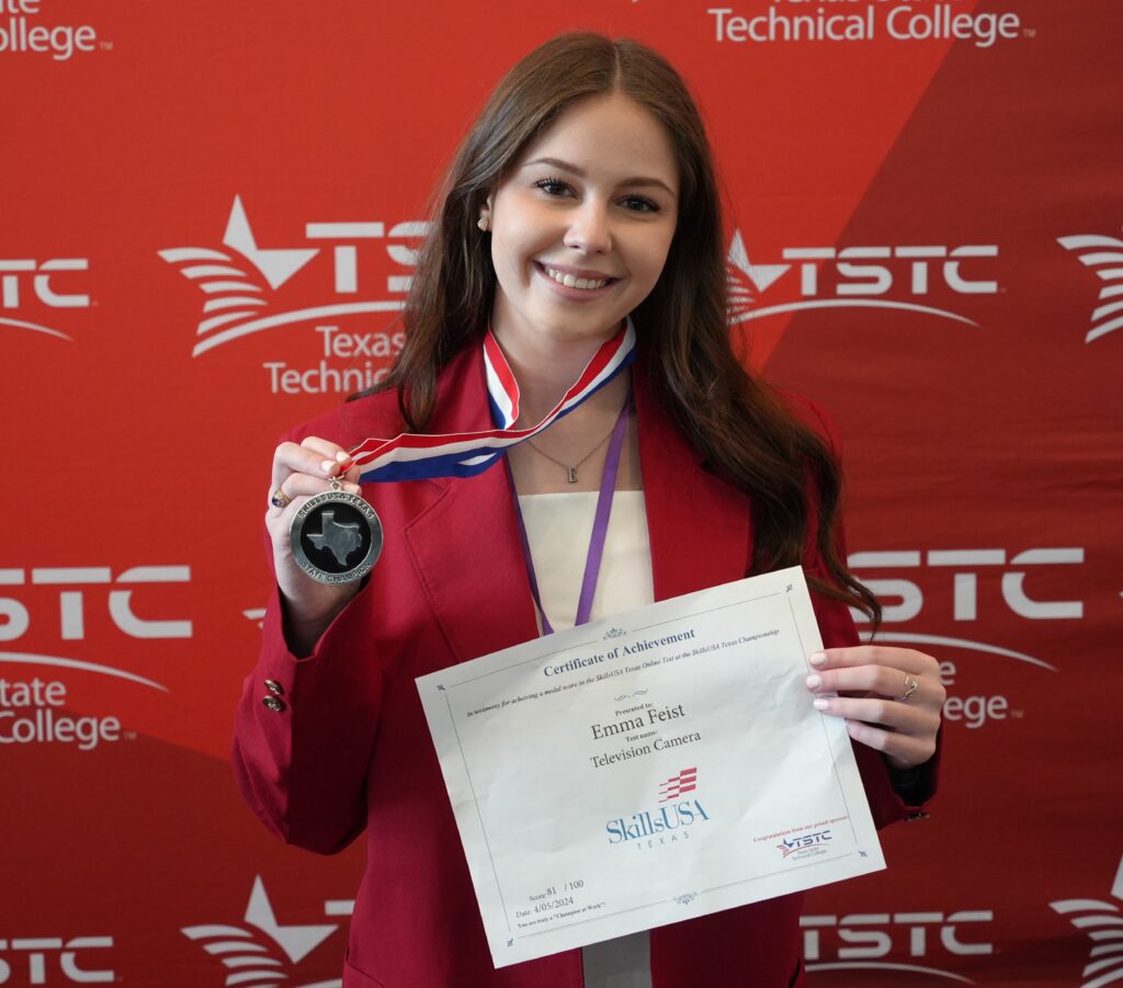 A young woman wearing a red blazer displaying an award